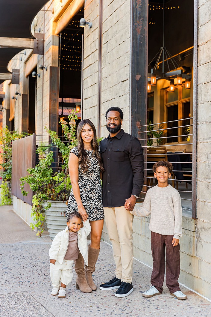 well dressed photogenic family taking a photo against neat architecture that compliments their outfits perfectly