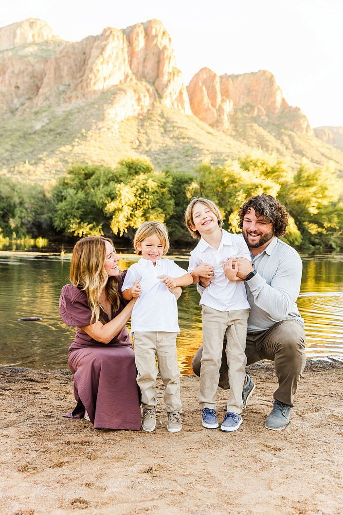 mom and dad tickling their little boys at the river