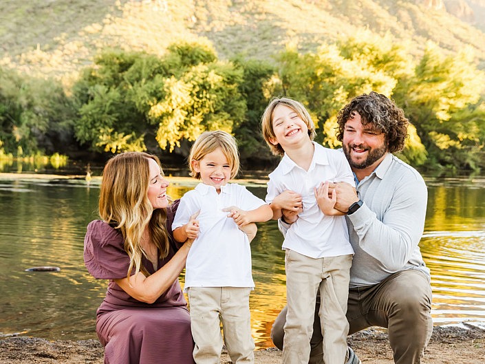 mom and dad tickling their little boys at the river