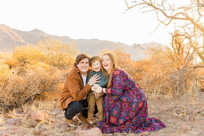 family squatting down by little boy in the arizona morning sun by superstition