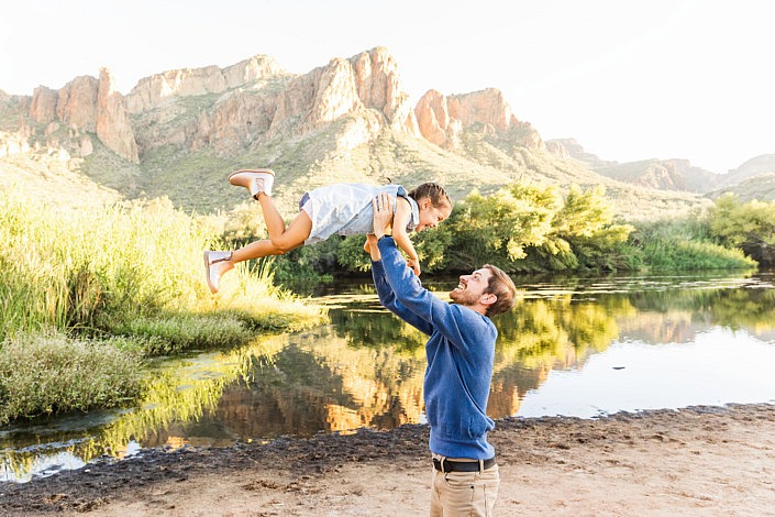 dad holding up daughter at the river