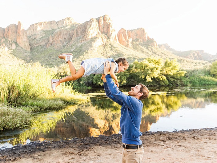 dad holding up daughter at the river