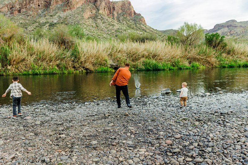 dad and boys skipping rocks at the river during their family photo session