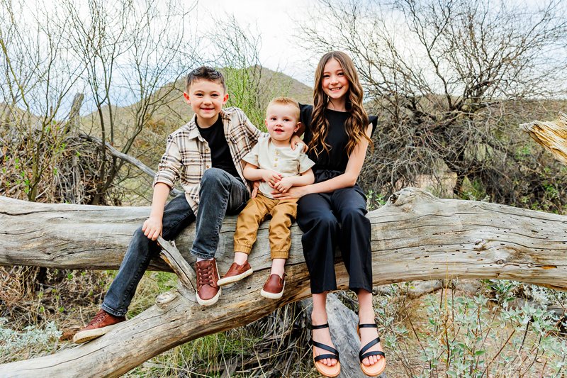 kids sitting on a fallen down tree